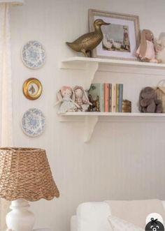 a living room filled with furniture and pictures on the wall next to a lamp in front of a window