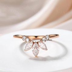 a gold ring with three pear shaped diamonds on the front and side, sitting on top of a white plate