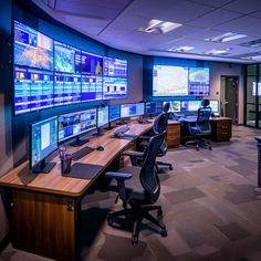 a control room with multiple monitors on the wall and desks in front of them