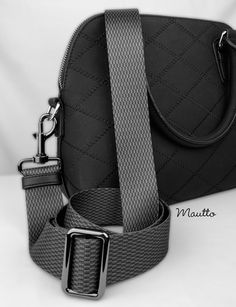 a black and white photo of a handbag with a silver buckle on it's strap