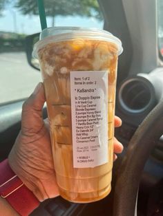 a person holding up a cup of iced coffee in their hand with information on it