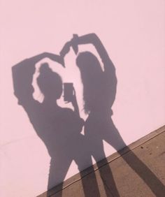 the shadow of two people standing next to each other in front of a white wall