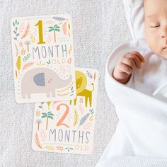 a baby laying on top of a white blanket next to a card with an elephant