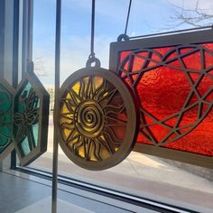 two stained glass ornaments hanging from the side of a window