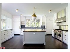 a large kitchen with white cabinets and stainless steel appliances in the center, along with an island