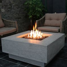 a fire pit sitting on top of a black tile floor next to two couches