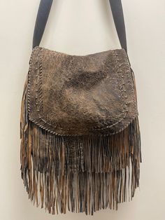 Safari tan full grain lambskin leather from New Zealand has hand whipstitched details, brass colored buckle and grommets on strap. This large sized crossbody fringed bag has lots of storage and zippered pocket on the backside of the bag. Due to lighting used during photography, actual finishes may vary from imagery. Exterior: Magnetic closure. Zip compartment on back. Interior: Satin lined. Center zip compartment. Dimensions: 15W x 14H x 2D (6-7" fringe) Adjustable Strap: 19-21 inch drop. Made i Large Crossbody Bag, Large Crossbody Bags, Fringe Bags, Brass Color, Lambskin Leather, Magnetic Closure, New Zealand, Crossbody Bag, Adjustable Straps