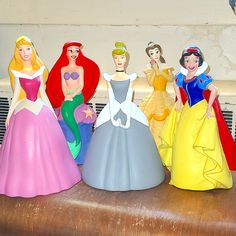 several disney princess figurines sitting on top of a wooden table next to each other