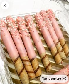 there are many pink and white candy sticks on a plate with some sprinkles