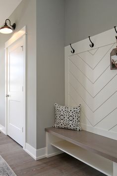 there is a bench in the hallway with two coat hooks on the wall above it