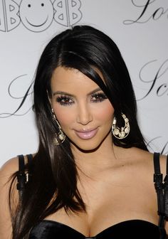 kim kardash is posing for the camera in her black dress and gold hoop earrings