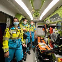 three people in yellow and blue uniforms are standing on a train with medical equipment around them