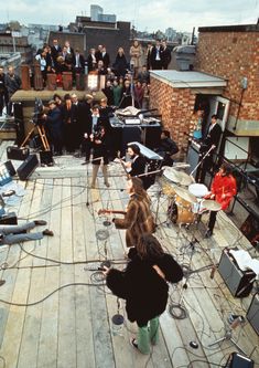 a group of people standing on top of a roof next to each other with musical instruments