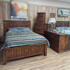 a bed room with a neatly made bed and dressers