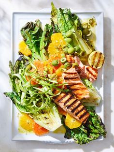 a white plate topped with meat and veggies on top of a bed of lettuce