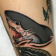 a close up of a person's leg with a shark tattoo on it,