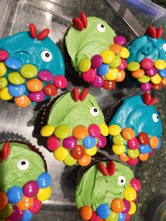 cupcakes decorated to look like fish with colorful candies on them in a plastic container