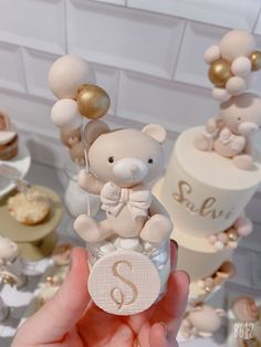 a hand holding a small teddy bear on top of a cake