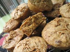 a pile of cookies sitting on top of a table next to a glass container filled with muffins