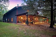 a large house sitting on top of a lush green field next to a wooded area