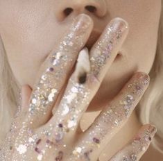 a close up of a person with glitter on their hands and fingers in front of her face