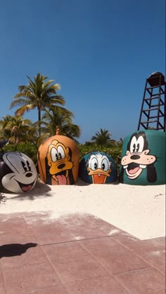 several cartoon characters painted on pumpkins in front of palm trees