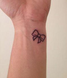 a small tattoo on the wrist of a woman with a bowknoted design