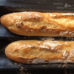 two long loafs of bread sitting on top of a black cloth covered baking pan