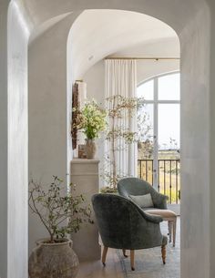 an arch leading into a living room with a chair and potted plant