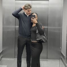 a man and woman taking a selfie in an elevator with their cell phone up to their ear