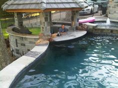 a man sitting on the edge of a pool next to a gazebo and water slide