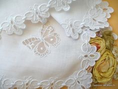 white lace and flowers are on the table cloth, which has been embroidered onto it