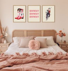 a bed with two pictures on the wall above it and a pink pillow in front of it