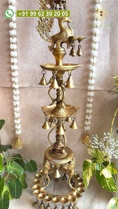 there is a tall metal candle holder with bells on the top and beads around it