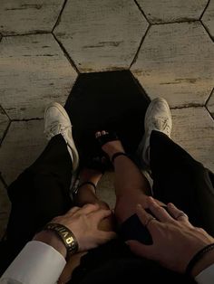 two people holding hands while sitting on the ground