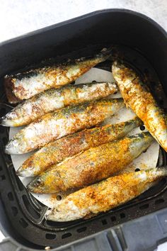 an air fryer filled with fish on top of a table