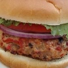 a hamburger with lettuce, tomato and onion sitting on top of a white plate