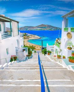 an alley leading to the beach with blue water and white buildings on both sides in front of it