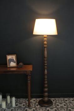 a lamp that is on top of a table next to candles and a framed photo