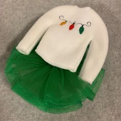 a white sweater and green tutu skirt with christmas lights on the collar is shown