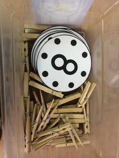 a container filled with wooden clothes pins and a black and white polka dot design on the top