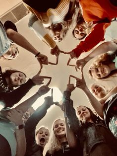 a group of people standing in a circle with their hands together and looking up at the camera