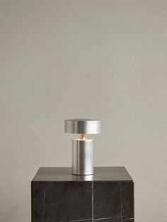 a table lamp sitting on top of a black and white marble block with a silver base