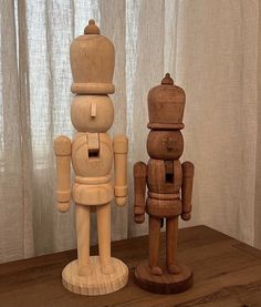 two wooden toy figurines sitting on top of a table next to a window