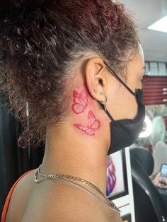 a woman with a tattoo on her neck wearing a face mask and looking at the camera