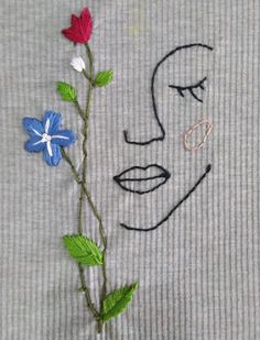 a drawing of a woman's face with flowers in front of it on a piece of fabric