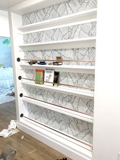 there is a book shelf with books on it in the room that has been painted white