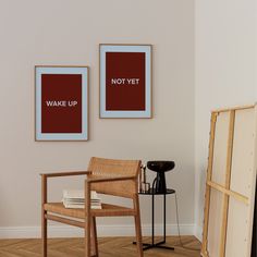 two framed pictures hang on the wall above a chair and side table in an empty room