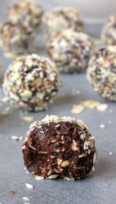 chocolate truffles with coconut flakes and chopped nuts on a baking sheet