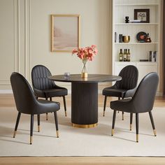 a dining table with four chairs around it and a vase on the table next to it